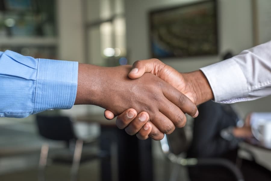 Two people shaking hands across a meeting table